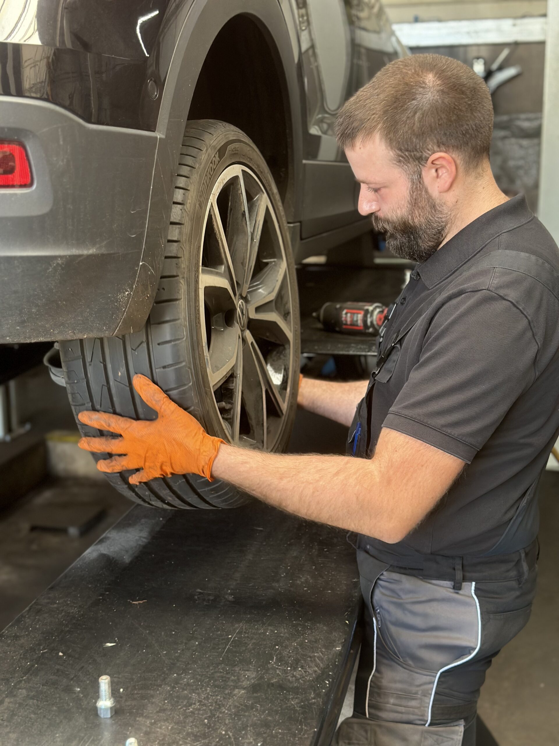 KfZ-Techniker wechselt Reifen am PKW